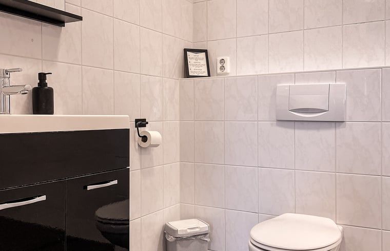 Modernes Badezimmer im Ferienhaus in De Cocksdorp, Texel, mit glatten Fliesen und Annehmlichkeiten auf den Watteninseln.