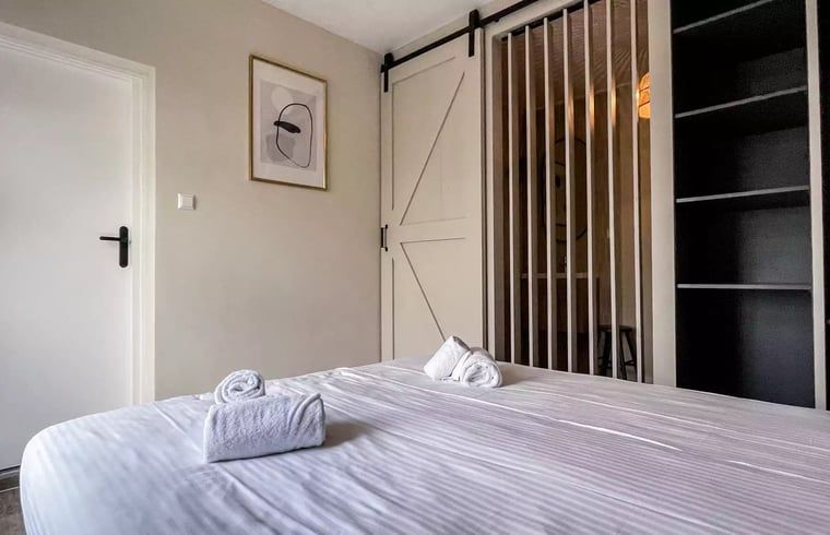 Stijlvolle slaapkamer in Huisje in De Cocksdorp, Texel, met houten schuifdeur en moderne inrichting.