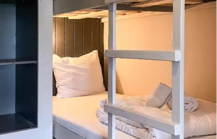 Knusse slaapruimte in Huisje in De Cocksdorp, Texel, met stapelbed en zachte kussens.