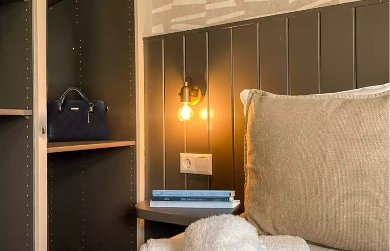 Slaapkamerhoek in Huisje in De Cocksdorp, Texel, met leeslamp en comfortabele bedden.