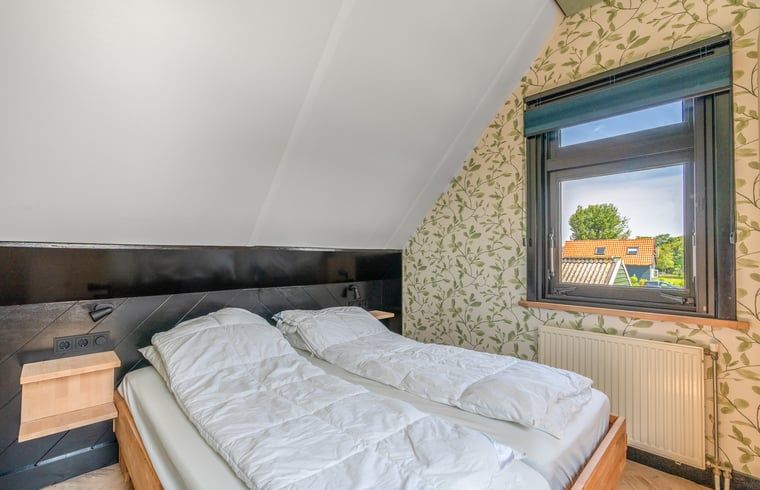 Gemuetliches Schlafzimmer im Ferienhaus in De Cocksdorp Texel mit Blick auf den Garten.