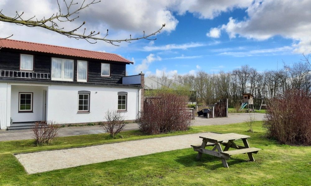 Aussenansicht des Ferienhauses Paal 86 Texel in De Cocksdorp mit Picknicktisch und Garten.