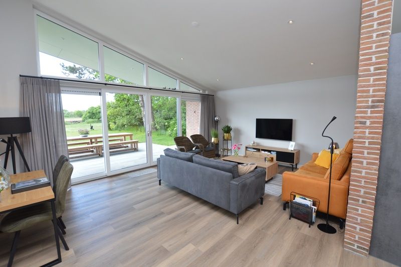 Bright living room of Orchismient 49 vacation home in De Koog, Texel with views of greenery and spacious seating area.