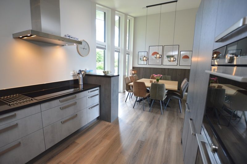 Open kitchen and dining area of Orchismient 49 vacation home in De Koog, Texel with lots of light and modern decor.