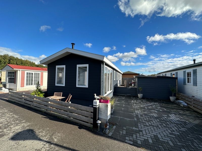 Chalet Bregkoog 52 in De Koog Texel mit grosser Auffahrt und blauem Himmel.