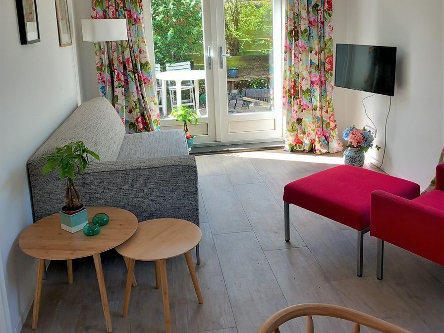 Cozy living room in Huisje Quirijn, De Koog Texel with colorful curtains and French doors to the garden.