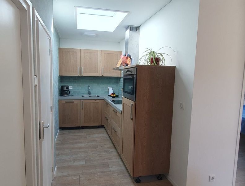 Compact kitchen in Cottage Quirijn, De Koog Texel with sleek wooden finish and modern appliances.