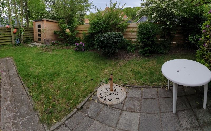 Spacious garden of vacation home Huisje Quirijn, De Koog Texel with terrace and green fence.