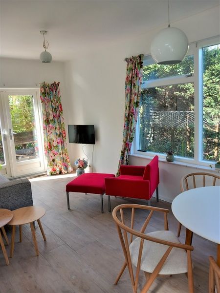Stylish living space in Huisje Quirijn, De Koog Texel with red armchairs and lots of natural light.
