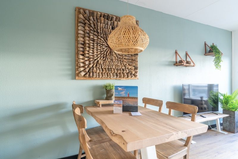 Esszimmer mit Holztisch im Appartement Juliana 140 Insel- und Meerblick, De Koog, Texel fuer stimmungsvolle Mahlzeiten.