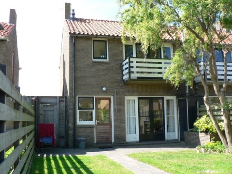 Backyard of The Duinputter vacation home in De Koog Texel with balcony and green view.