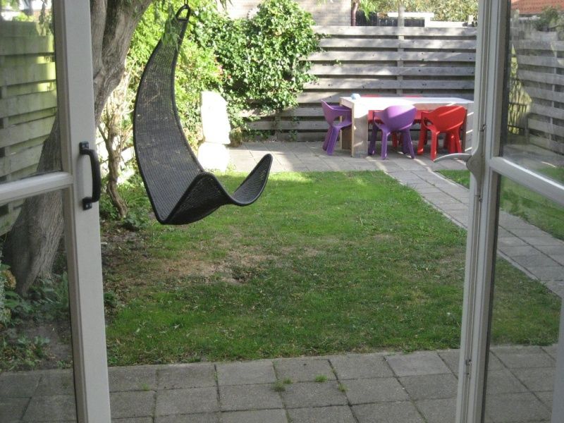 Cozy garden of The Duinputter in De Koog Texel with rocking chair and colorful chairs.