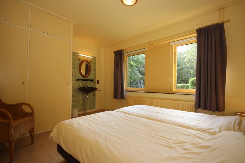 Bedroom in Landhuis Landleven No. 81, vacation home in De Koog, Texel with double bed and view of nature.