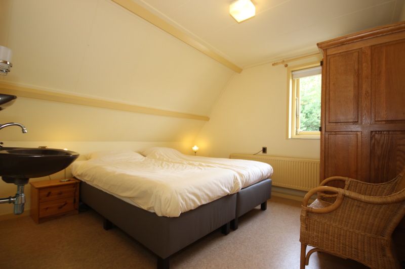 Cozy bedroom in Landhuis Landleven No. 81, vacation home in De Koog, Texel with double bed and wooden furniture.