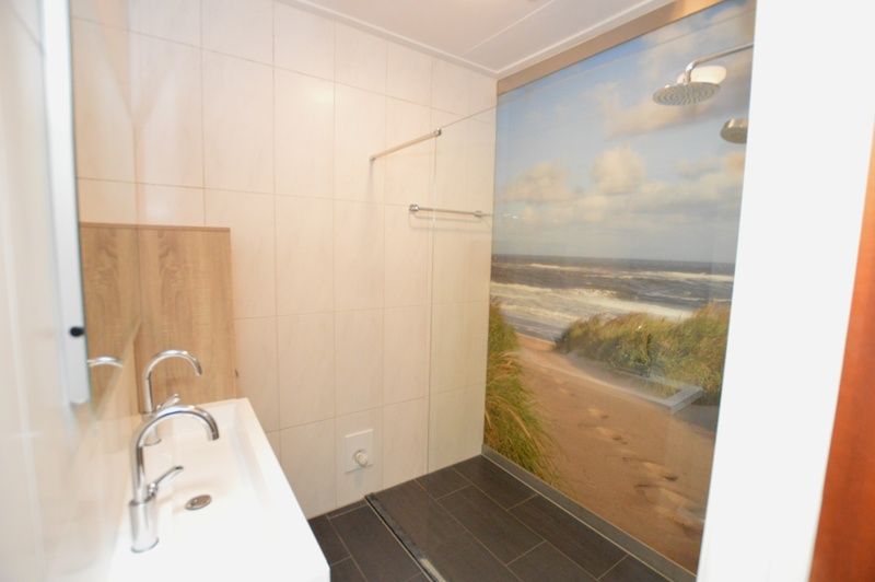 Modernes Badezimmer in Orchismient 45 grosses Ferienhaus De Koog Texel mit begehbarer Dusche und Strandthema.
