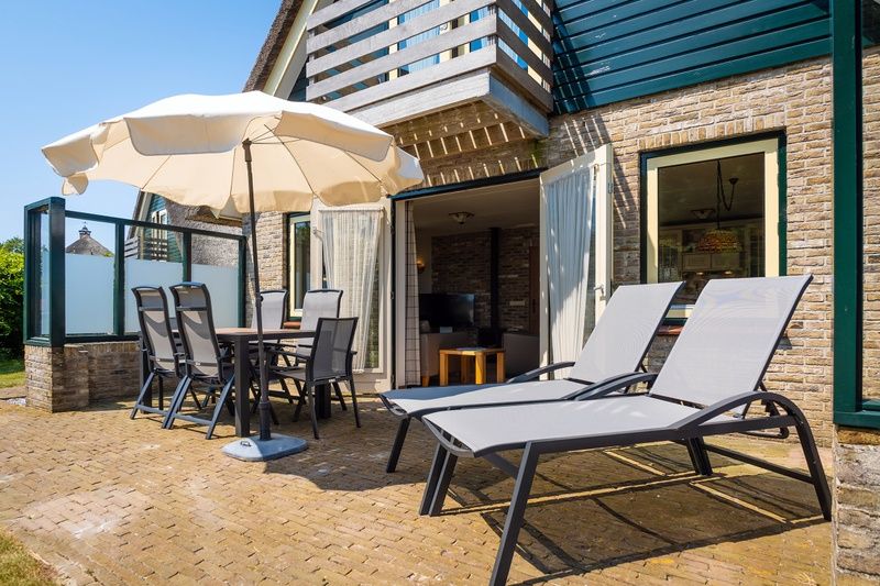 Sunny terrace at Villa, De Koog, Texel with deck chairs and parasol for relaxing moments.