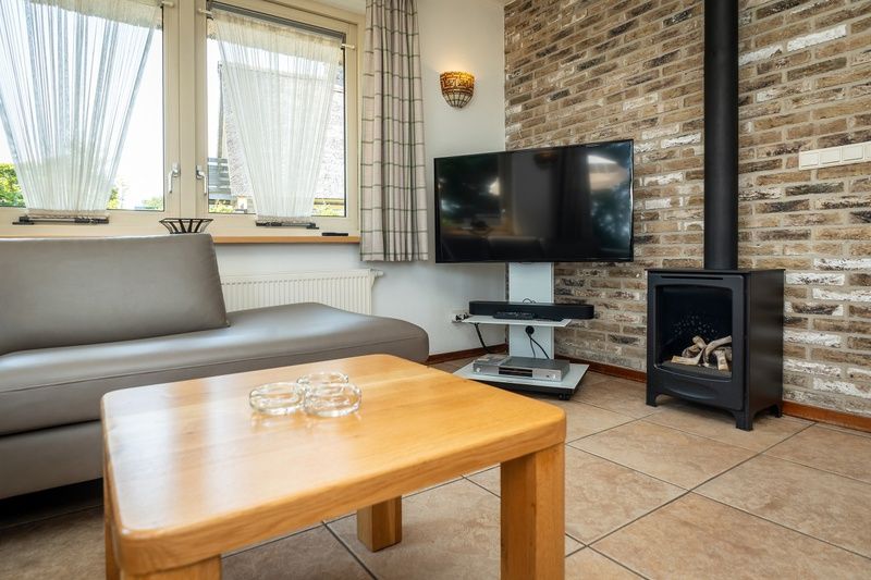 Modern living room in Villa, De Koog, Texel with flat-screen TV and cozy fireplace.