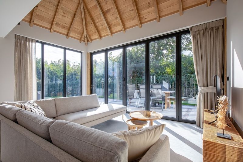 Bright living room of Villa Flo, Texel with large windows and views of the garden.