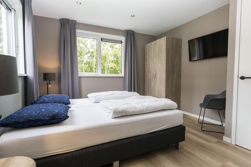 Bedroom in Villa 17, De Koog, Texel with comfortable double bed and view of green nature for ultimate relaxation.