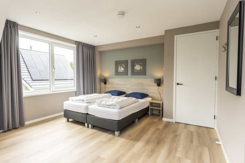Spacious bedroom with large window in Villa 17, De Koog, Texel offers plenty of natural light and a serene atmosphere.