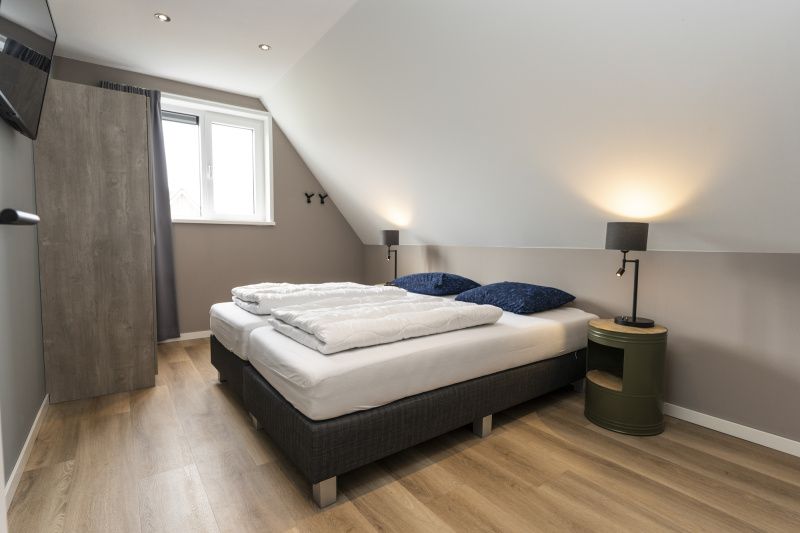 Villa 17 in De Koog, Texel offers a bedroom with modern design and large windows for a light and spacious feeling.