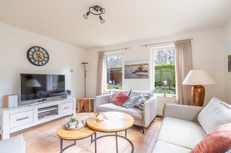 Modern living room of vacation home Honeysuckle 81 in De Koog, Texel with flat-screen TV and cozy furnishings for a relaxing stay.