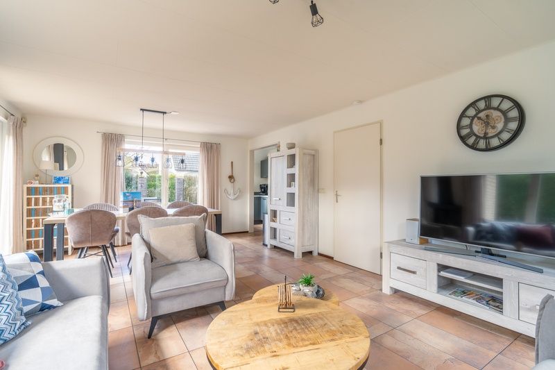 Spacious living room of vacation home Kamperfoelie 81, De Koog, Texel with dining area and comfortable sitting area, ideal for family and friends.