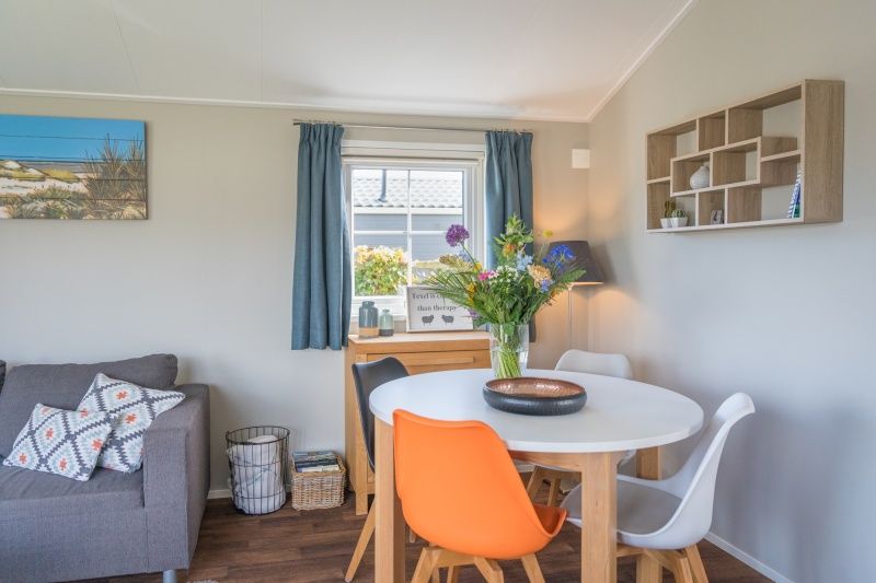 Dining area Chalet Bregkoog 227, Chaletpark Bregkoog, De Koog, Texel with modern chairs and decorative flowers.