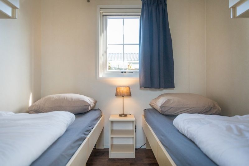 Second bedroom in Chalet Bregkoog 227, Chaletpark Bregkoog, De Koog, Texel with two single beds and atmospheric lighting.