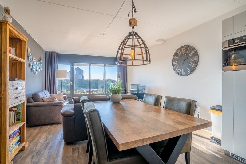 Eetkamer met houten tafel in Appartement Juliana 048, geniet van maaltijden met uitzicht op de natuur in De Koog, Texel.