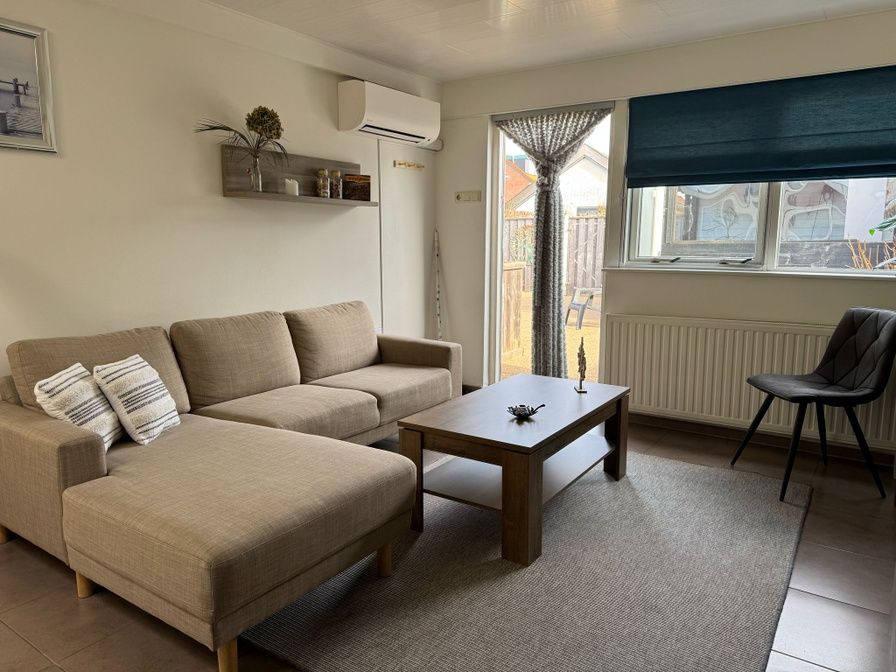 Cozy living room of Duo bungalow in De Koog, Texel with comfortable seating area and lots of natural light.