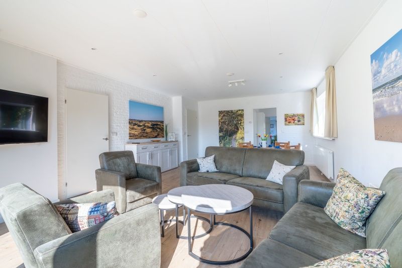Bright living room of Orchismient 14 vacation home De Koog Texel with comfortable sofas and access to dining area.