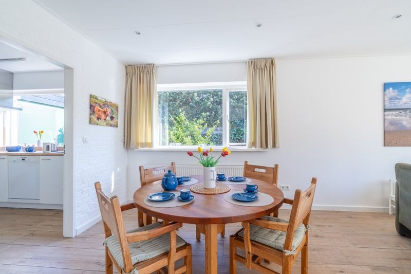Dining area in Orchismient 14 vacation home De Koog Texel with round table and garden view.