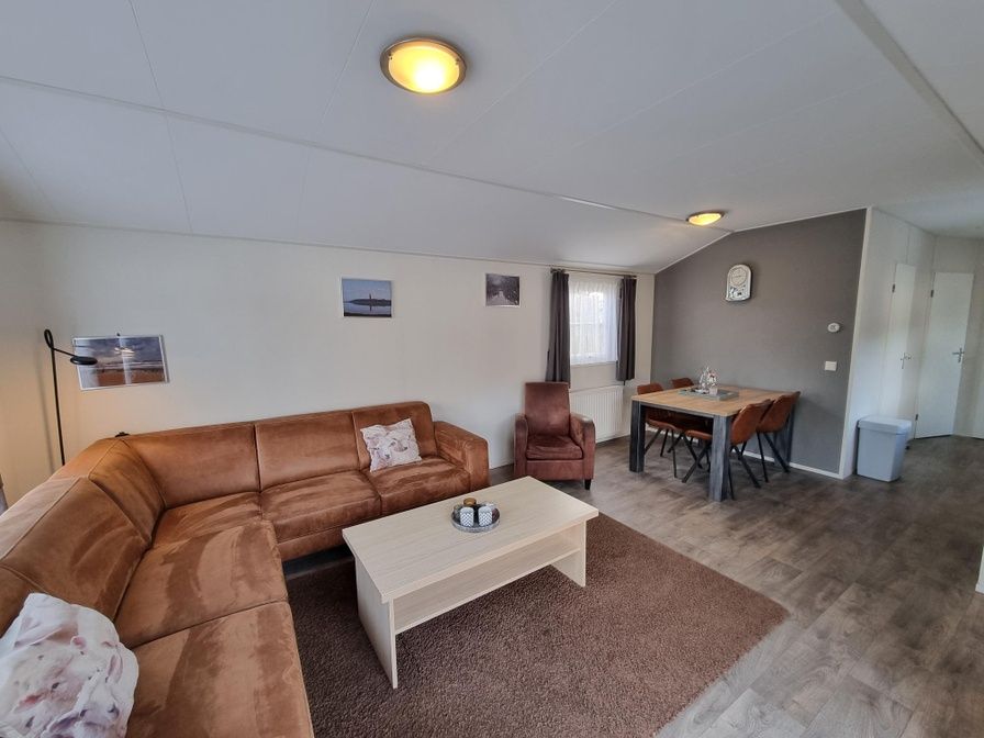 Cozy living room in Chaletpark Bregkoog - Chalet Bregkoog 235, De Koog, Texel with comfortable sitting area and dining area.