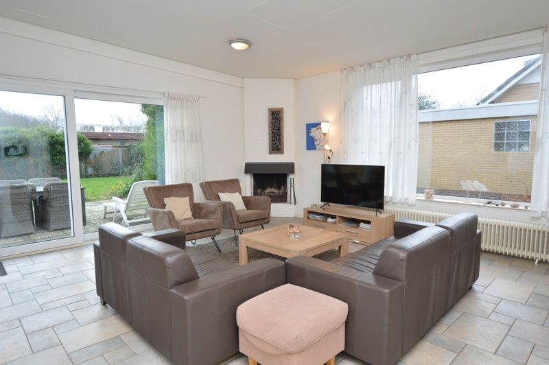 Cozy living room of vacation home Epelaan 31 in De Koog, Texel with modern furnishings and garden views.