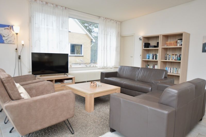 Bright living room with bookcase in vacation home Epelaan 31, De Koog, Texel, perfect for reading lovers.