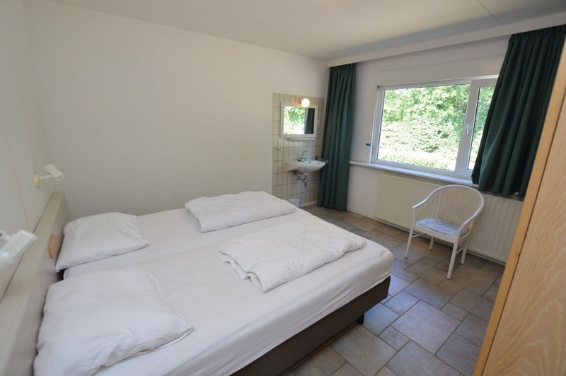 Comfortable bedroom with large window in Epelaan 31, vacation home in De Koog, Texel, overlooking nature.