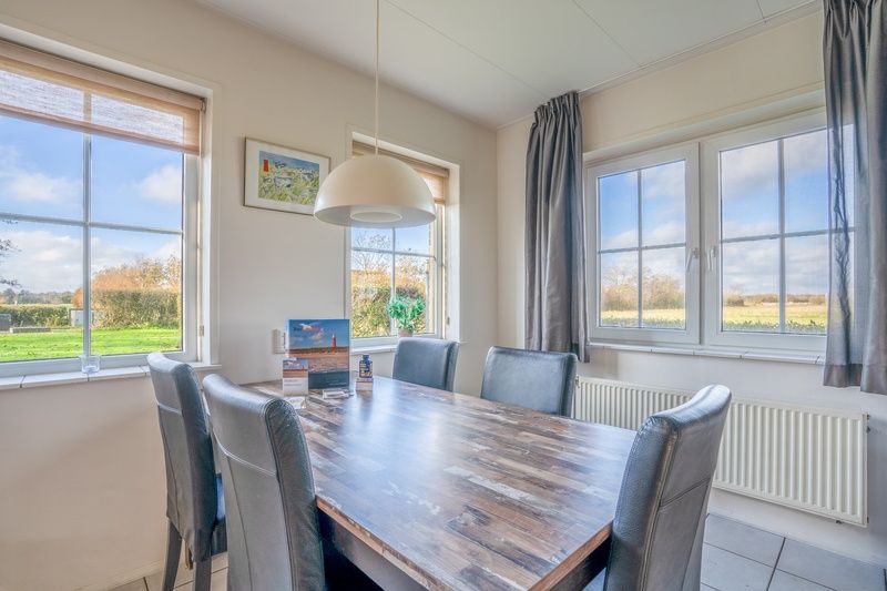 Dining room in vacation home Maaikeduinweg 13, De Koog, Texel with large windows and beautiful views of the surrounding nature.
