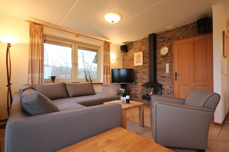 Gezellige woonkamer in Villa, De Koog, Texel, met comfortabele zithoek en open haard voor een knus verblijf.