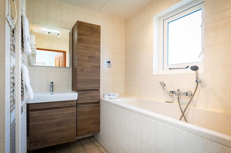 Ruime badkamer in Villa, De Koog, Texel, met ligbad en natuurlijke lichtinval voor ontspanning.