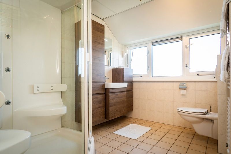Badkamer in Villa, De Koog, Texel, met ruime douche en toilet, ideaal voor comfort tijdens je verblijf.