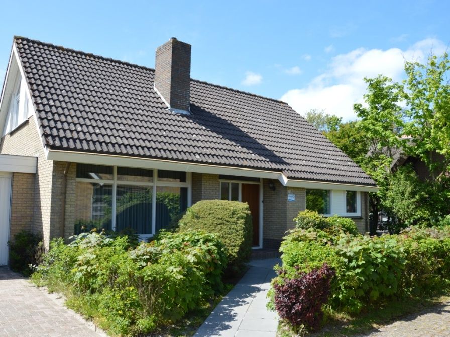 Charming vacation home Orchismient 27 in De Koog, Texel, with green garden and inviting facade.