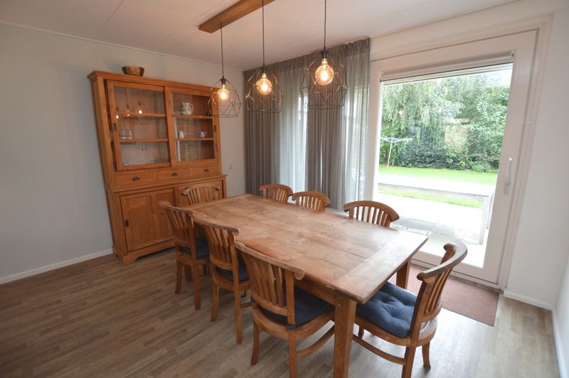 Dining area in Orchismient 27, De Koog, Texel, with wooden table and garden view.