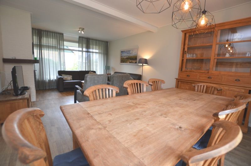 Open living room and dining area in vacation home Orchismient 27, De Koog, Texel, with rustic furnishings.