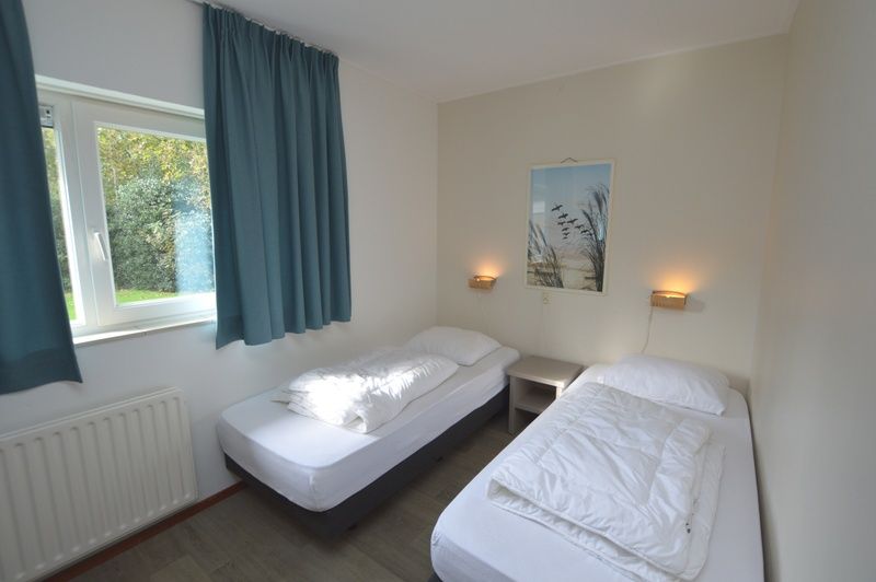 Second bedroom in Orchismient 27, De Koog, Texel, with two single beds and garden view.