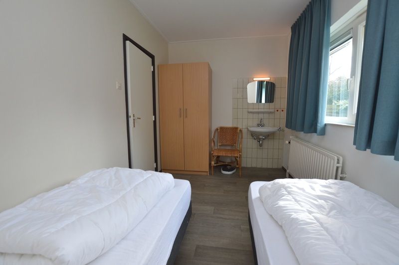 Cozy bedroom in vacation home Orchismient 27, De Koog, Texel, with single beds and sink.