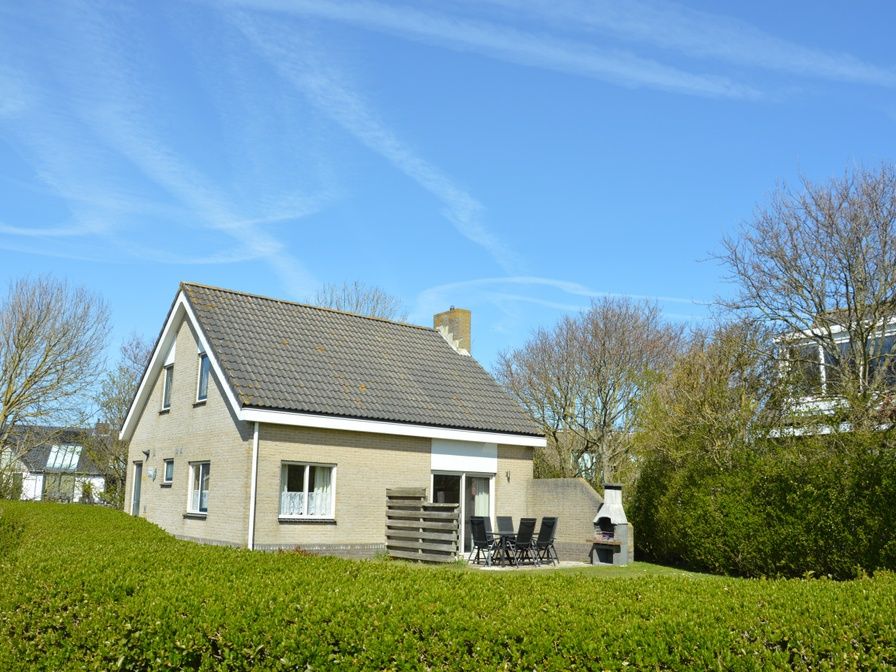 Vacation home Stappeland 207 in De Koog, Texel offers a charming exterior surrounded by greenery, ideal for a relaxing stay.