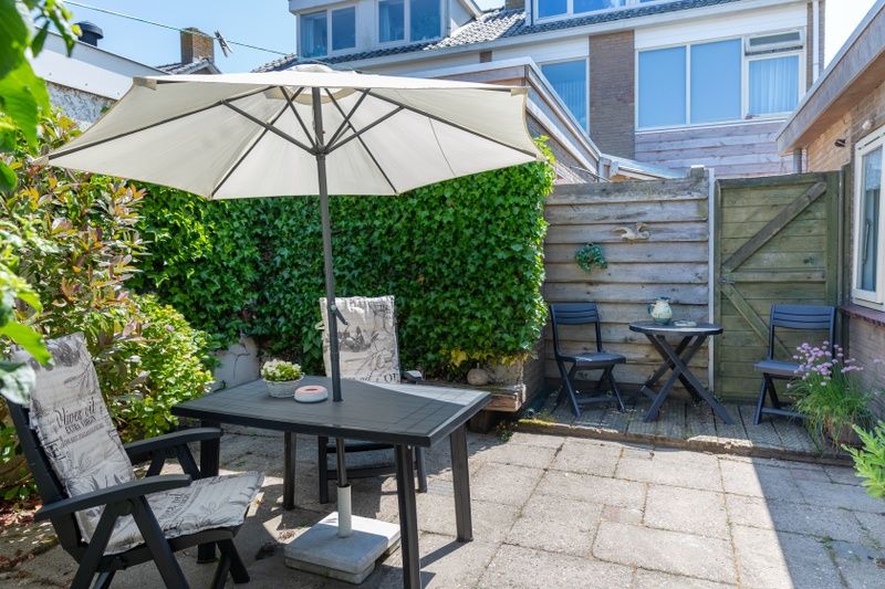 Private garden of Bungalow 9708 in De Koog Texel, with shaded seating area and green surroundings.