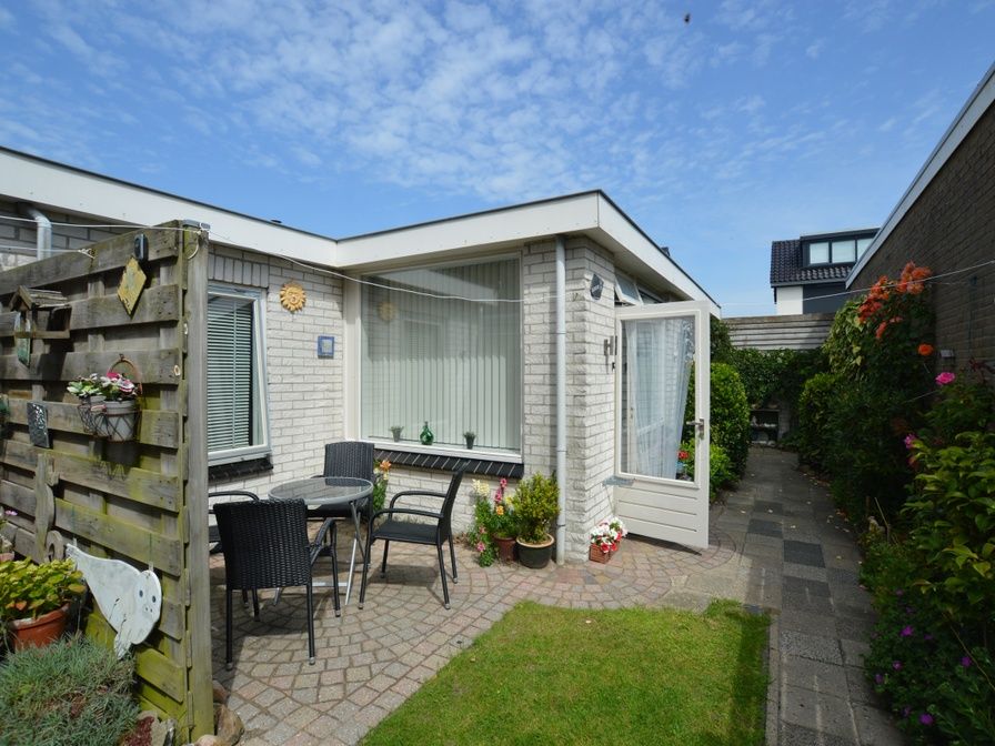 Cozy terrace at Plevierstraat 18 vacation home in De Koog, Texel with outdoor seating and flowering garden.