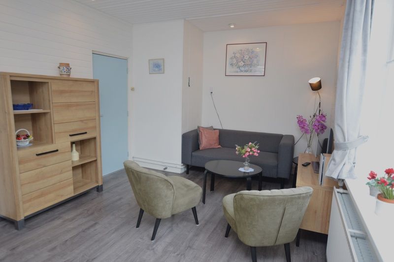 Modern living room in vacation home Plevierstraat 18, De Koog, Texel with comfortable seating area and wooden cupboard.